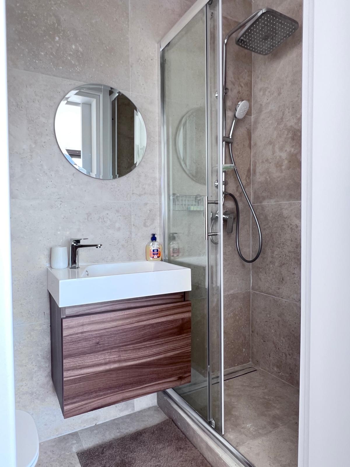 Elegant bathroom sink with round mirror and glass shower